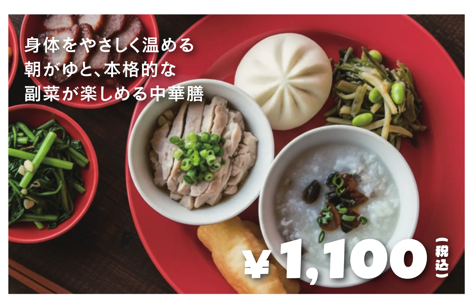 赤い器に盛られた中華粥、蒸し鶏、焼豚、肉まん、青菜炒めの朝食