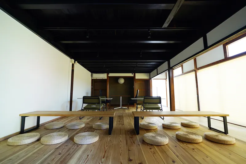 母屋の座敷。黒い天井と木の床、座布団が並ぶ