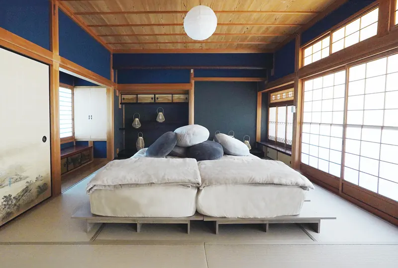 竹の間の寝室。濃い青の壁と障子、低いベッドにグレーの寝具