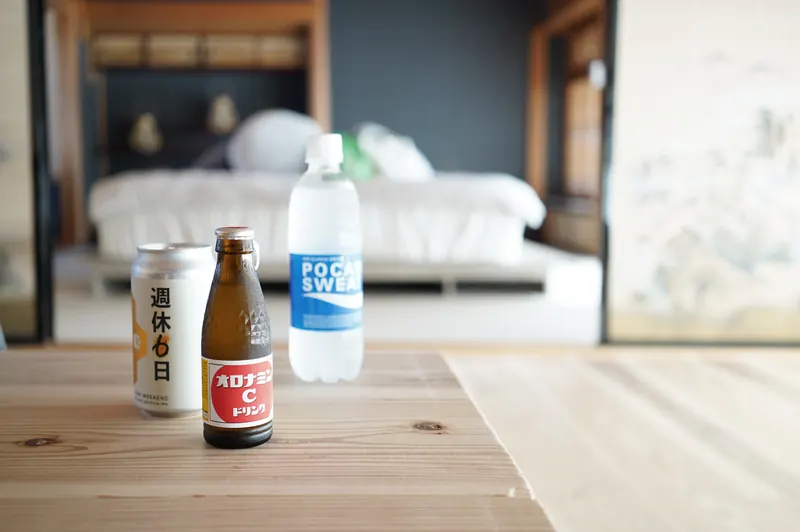 竹の間のテーブルに置かれたオロナミンCとポカリスエット。奥にベッド